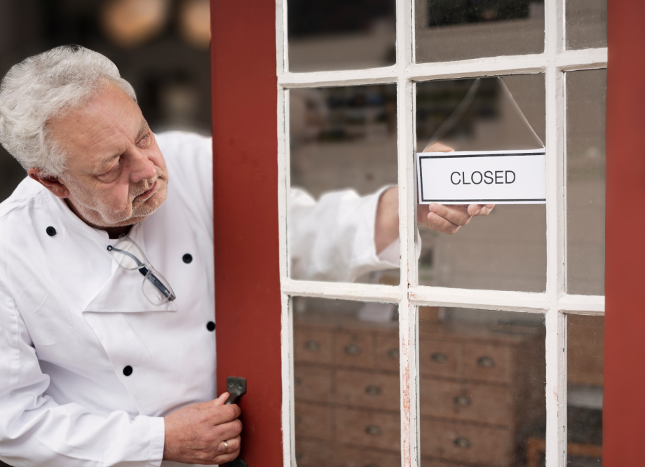 restaurant owner hangs a "closed" sign on the door