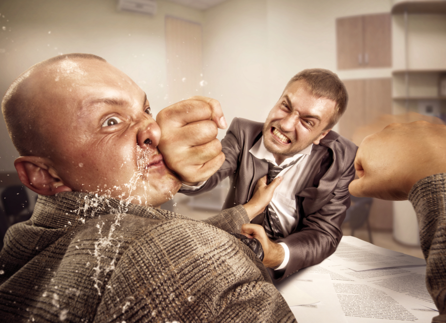 two angry men in suits fight in an office. One man punches the other in the nose while the other attempts to grab and punch him.